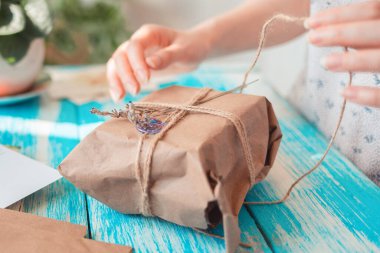 Dişi bir el, kurumuş çiçeklerle el işi kağıdına doldurulmuş bir paketi açıyor. Yakın plan. Paket alma ve boks yapma kavramı.