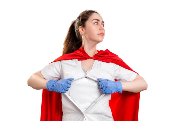 A doctor wearing medical gloves and a red superhero Cape, tears her coat on her chest. Isolated on white background. The concept of the Power of a super hero for medicine.