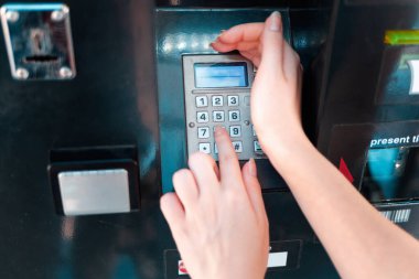 ATM ve banka işlemleri. Elini örten kadın, banka kartından şifreyi giriyor. Kapat..