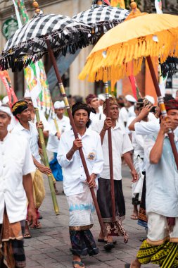 Galungan Tatili. Şemsiyeli adamların şenlik alayı. Bali Adası, Endonezya. 26.12.2018 Dikey yönelim