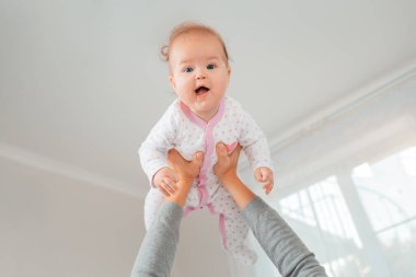 Bir anne mutlu çocuğu kollarına aldı. Alt manzara. Beyaz iç mekan. Annelik ve mutlu çocukluk kavramı..