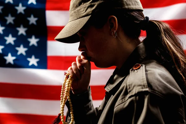 阵亡将士纪念日士兵的画像一个女人拿着念珠祈祷 把念珠举到嘴边 背景是美国国旗 美国假日和宗教的概念 — 图库照片