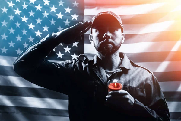 悼念日一名身穿制服的士兵手持蜡烛 在美国国旗的背景下致敬 黑人和白人 美国国定假日和爱国主义的概念 — 图库照片