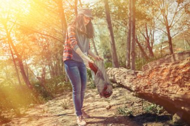 Kadın gönüllü, plastik çöpleri temizlemeye yardım ediyor. Dünya günü ve çevresel gelişim kavramı. Renkli ve hafif.