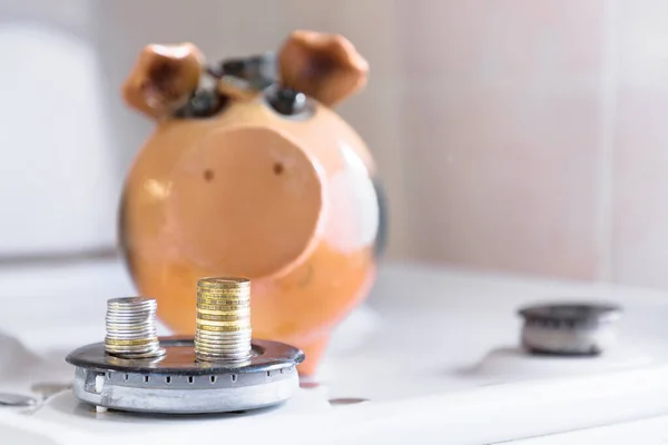 The concept of insurance or budget savings . two columns of coins on the gas burner on the background of the piggy Bank with copy space. — Stock Image Concept Insurance Budget Savings Two Columns Coins Gas Burner Background Stock Picture