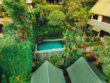 Parlak bitki örtüsünün arka planında havuzun yanındaki genç kız..