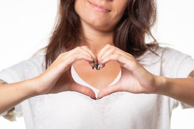 Bulanık gülümseyen bir kadın elleriyle bir kalp işareti gösterir. Ellerinin yakın plan bir görüntüsü. Dünya Kalp Günü konsepti.