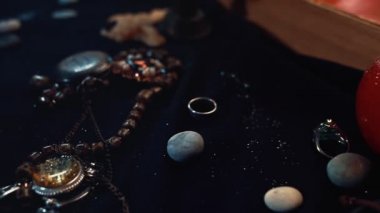 Kehanet ve sihir. Mücevherler, kitap, rünler ve haritayla dolu bir masada kamera hareketi. Falcının mallarına yakın çekim.