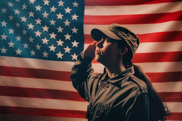 記念日だ アメリカ国旗を背景に 制服を着た女性兵士が敬礼する サイドビュー アメリカの国民の祝日と愛国心の概念 — ストック写真