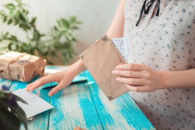 Bir kadın elinde bir mektupla bir zarf tutuyor. Eller yakın çekim. Posta iletisi kavramı.