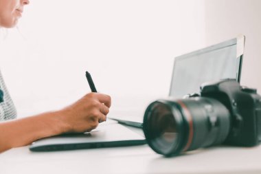 Dijital grafik tablet kullanan ve resimleri rötuşlamak için kalem çizen genç bir kadın. İlk planda kamera. Kapat..