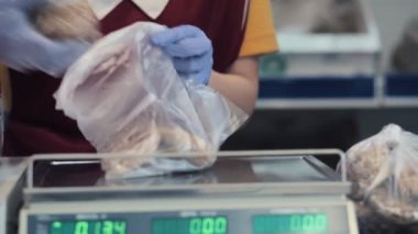 Üniformalı, lastik eldiven takan, plastik torbada zencefilli ekmek paketleyen bir çalışan. Eller yakın plan..