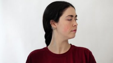 Farklı yönlere dönüp yanaklarında kızarıklık gösteren genç bir kadının portresi. Beyaz arka plan. Rosacea ve couperose konsepti.