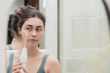 Çekici bir kız sivilcelere karşı darsonval bir cihaz kullanıyor..