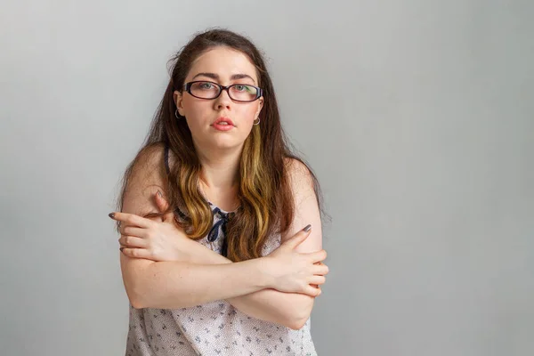 感情や人 眼鏡とブラウスの若いブルネットの女性は 肩で自分自身を抱きます 不確実性の感情 — ストック写真