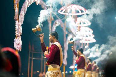 17.12.2019, Varanasi, Hindistan. Tapınakta kutsal dini tören Arati. Bir grup insan tütsü yakıyor. İyi geceler. Arka planda şemsiyeler var..