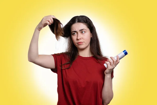 Retrato Uma Jovem Segurando Xampu Olhando Para Suas Pontas Cabelo — Fotografia de Stock