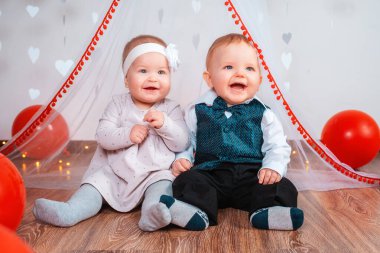 İki küçük mutlu çocuğun portresi, bir oğlan ve bir kız, kırmızı balonlarla kostüm giymiş. Sevgililer Günü ve romantizm kavramı.