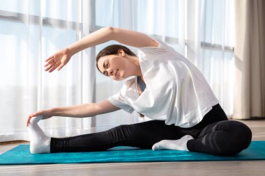 Spor giyim bölümünde yoga yapan genç ve güzel bir kadın. İçeride. Evde spor kavramı. Kapat..