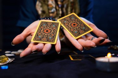 Haritacılık. Falcı avuçlarında iki Tarot kartı tutuyor. Kapatın. Kehanet, astroloji ve ezoterizm kavramı..