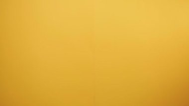 Bir erkeğin eli aşağıdan belirir ve baş parmağını kaldırır. Sarı arka plan. Pozitif iletişim ve jestler kavramı.