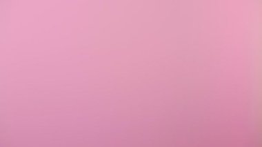 Bir kadının eli aşağıdan belirdi ve fırçasını sağa doğru salladı. Pembe arka plan. Jest kavramı.