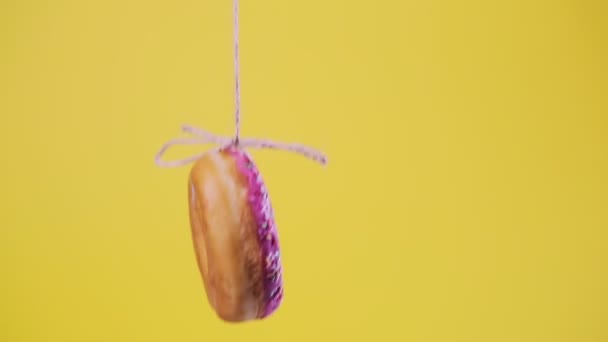 Пончик Рожевим Морозивом Підвішений Струні Стрибає Вгору Вниз Жовтий Фон — стокове відео