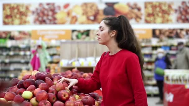 若い白人女性がスーパーでリンゴを摘む サイドビュー 売買と消費主義の概念 — ストック動画