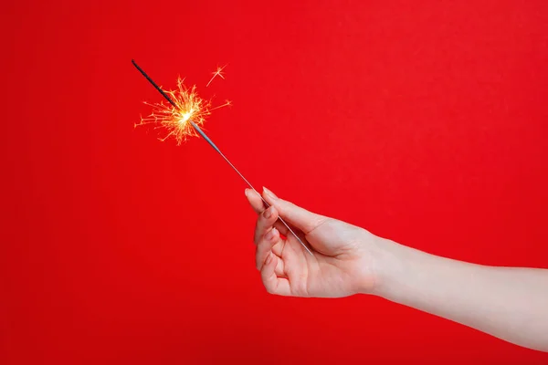 Giorno Scintille Mano Una Donna Tiene Uno Sparkler Sfondo Rosso — Foto Stock