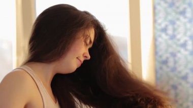 Saç bakımı. Siyah saçlarını saç kurutma makinesiyle kurutan gülümseyen güzel bir kadının portresi. Yan görünüm.
