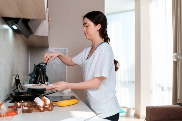 Young Caucasian Woman Prepares Breakfast Kitchen Puts Eggs Plate Side — Stock Photo, Image