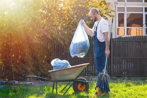 Jardinero Recoge Las Bolsas Hojas Las Pone Carro Sol Brilla — Foto de Stock