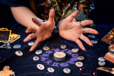 Falcı, rünlerle çevrili bir mum ve astrolojik bir çemberin parıltısını yaratır. Kehanet, astroloji ve geleceği tahmin etme kavramı..