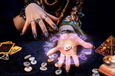 Falcı avucunun içinde parlak astrolojik bir çember olan bir rün tutuyor. Kehanet, astroloji ve geleceği tahmin etme kavramı..