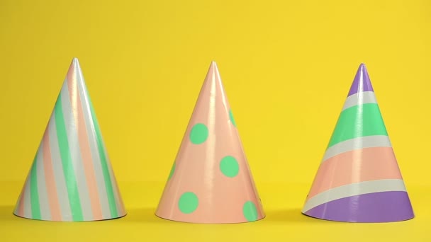 Tres Sombreros Multicolores Papel Festivo Pie Sobre Fondo Amarillo Mano — Vídeo de stock