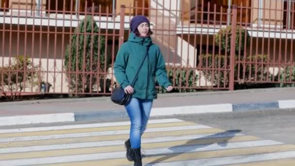 Eine Junge Kaukasierin Jacke Und Hut Läuft Über Einen Fußgängerüberweg — Stockvideo