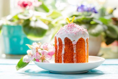 Paskalya tatili. Elma çiçeği ve vişne dalıyla süslenmiş bir paskalya pastası. Arka planda bitkiler ve çiçekler.