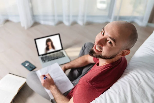 Een Kale Jongeman Werkt Een Laptop Schrijft Iets Papier Bovenaanzicht — Stockfoto