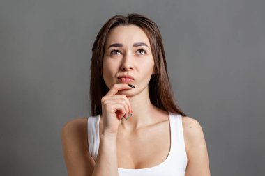 Fikir ve bilgi arama kavramı. Kafkasyalı genç bir kadının portresi yukarı bakıyor. Gri arka plan. Boşluğu kopyala.