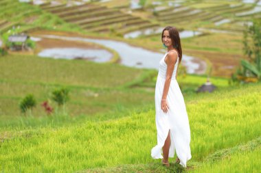 Pirinç tarlalarının arka planında poz veren bronz tenli genç bir kadın. Kapat.
