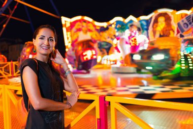 Genç ve güzel bir kadın lunaparkta eğleniyor. Eğlence ve yaz festivalleri kavramı.