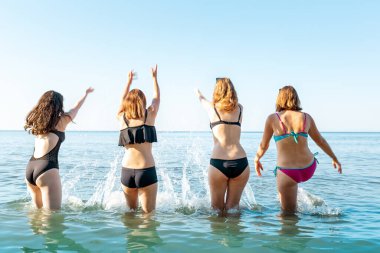 Suya su sıçratan bir grup genç kadın. Arka planda, deniz ve gökyüzü. Dikiz aynası. Uzayı kopyala Tatil kavramı, deniz tatili..