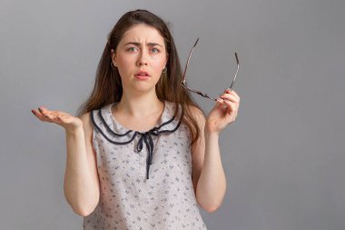 İnsanlar ve duygular. Bluz giymiş genç bir esmer, elinde bardaklarla ellerini şaşkınlıkla açıyor. Boşluğu kopyala.