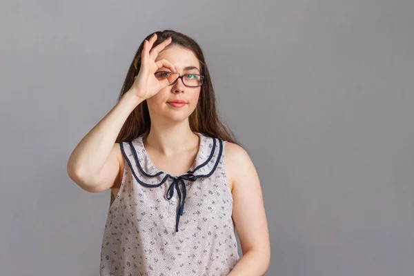 Emotions and people. Young woman in blouse and glasses, looking through her fingers. Copy space.