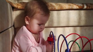 Eğitici bir oyuncakla oynayan beyaz bir bebeğin portresi. Çocuğun yüzünde güneş parıldıyor. Çocukları geliştirme ve eğitme kavramı