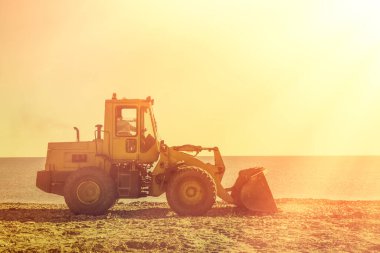 Deniz kıyısında buldozer. Arka planda deniz ve gökyüzü var. Skyline. Tint. Anlaşıldı..