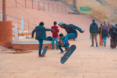 17.12.2019, Varanasi, Hindistan. Bir grup genç çocuk sokakta kaykaya biniyor..