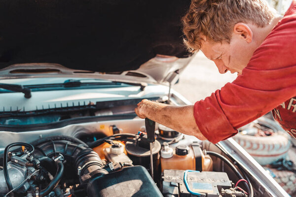 Понятие инвалидности людей и их адаптация к жизни. Инвалид c отверткой в руках ремонтирует двигатель. У него нет пальцев на руках. Инвалид с детства..
