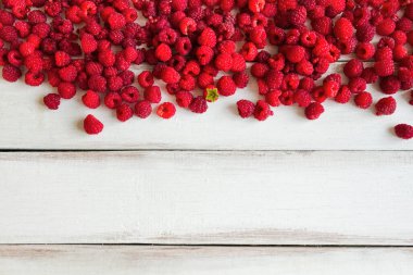 Olgun ahududu ve arka planda yeşil yaprak ile ahşap bir masa ve boşluğun bir kopyası.
