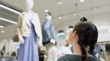 Bir kadın mağazada giysileri olan bir mankene bakıyor. Baş yakın plan. Dikiz aynası. Gerçek zamanlı. Tüketim ve alışveriş kavramı.